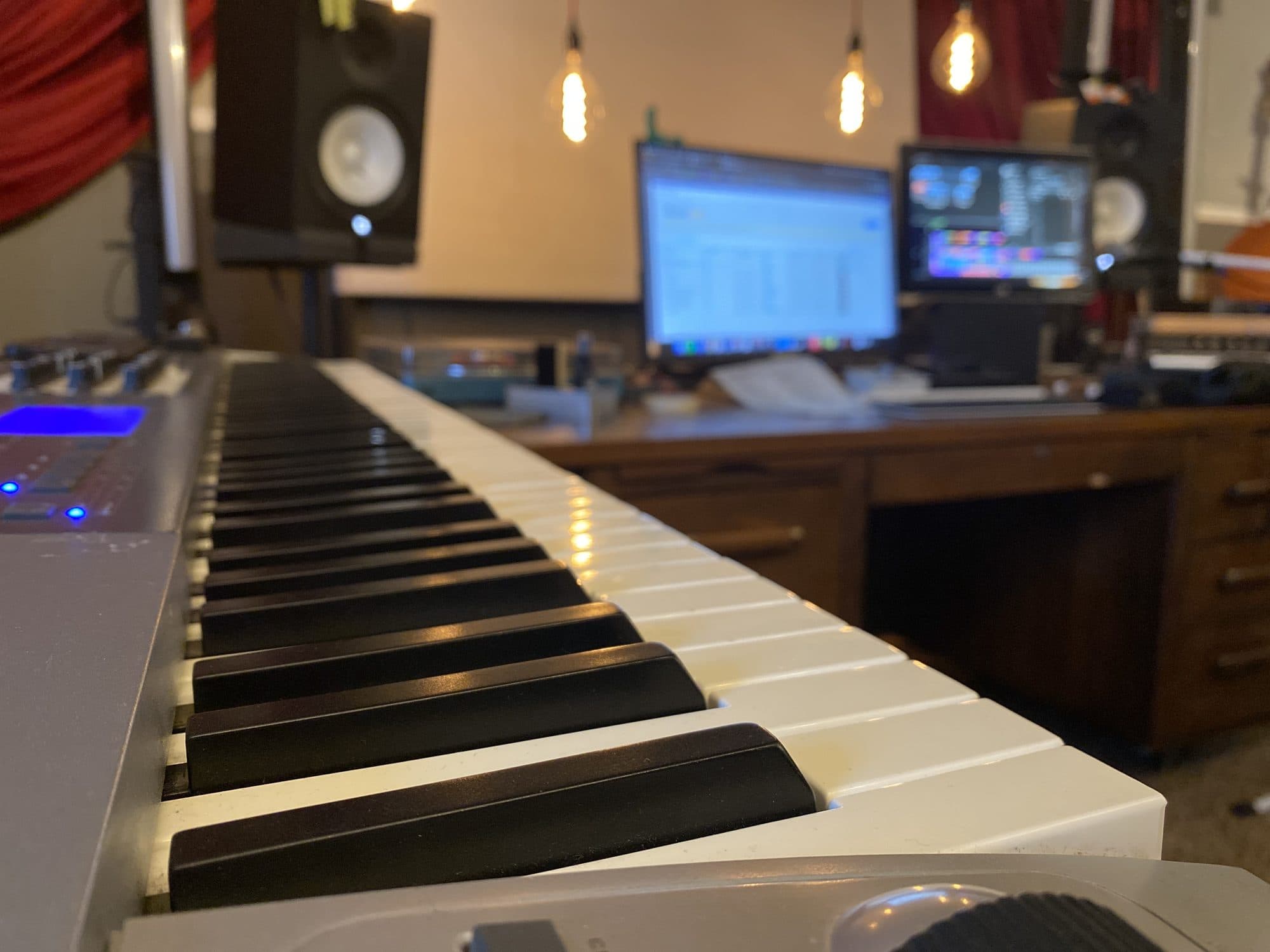 Keyboard and mixing desk in the Filament Productions studio, lit by hanging filament bulbs
